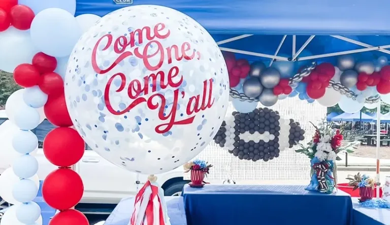 Red, white, and light blue balloon decorations with a clear balloon reading “Come One, Come Y’all.”