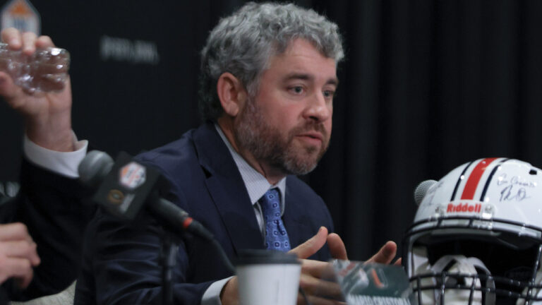 Ole Miss Rebels coach Pete Golding on the stage at a press conference with Miami Hurricanes coach Mario Cristobal