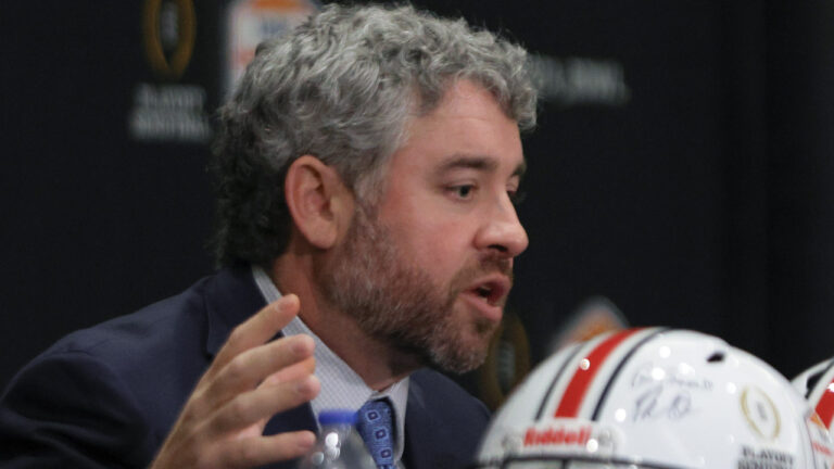 Ole Miss Rebels coach Pete Golding on the stage at a press conference with Miami Hurricanes coach Mario Cristobal