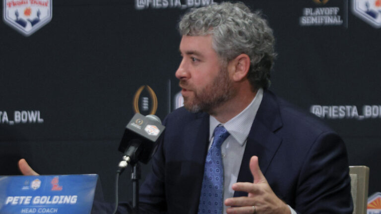 Ole Miss Rebels coach Pete Golding on the stage at a press conference with Miami Hurricanes coach Mario Cristobal