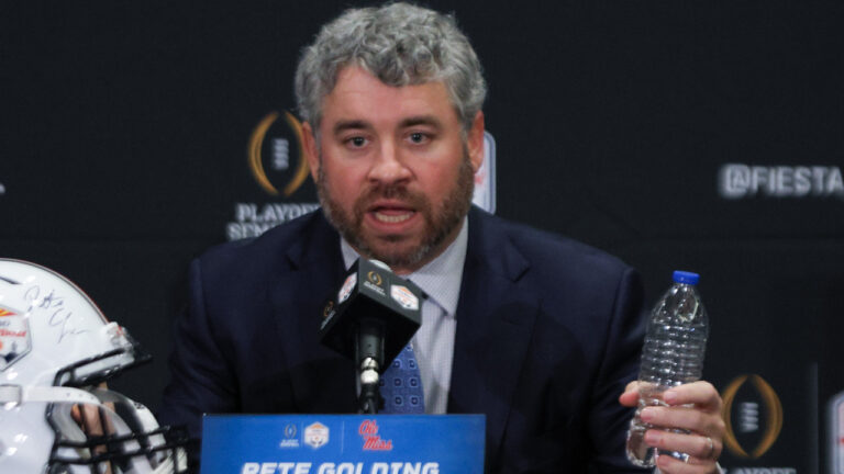 Ole Miss Rebels coach Pete Golding on the stage at a press conference with Miami Hurricanes coach Mario Cristobal