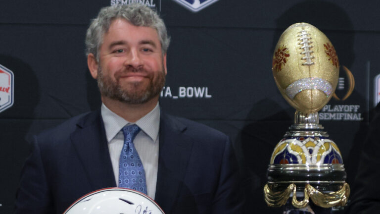 Ole Miss Rebels coach Pete Golding on the stage at a press conference with Miami Hurricanes coach Mario Cristobal